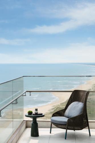 a chair on a balcony with a view of a beach at New World Hoiana Beach Resort in Hoi An