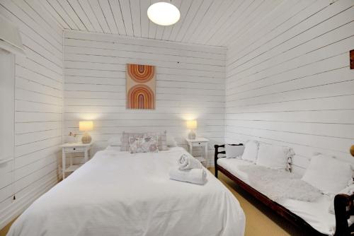 a white bedroom with a large bed and a couch at Home Away From Home Little White Cottage Mudgee in Mudgee