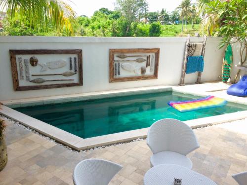 una piscina con 2 sillas y una mesa en Canggu - Pererenan Guesthouse " aBaliHouse ", en Canggu