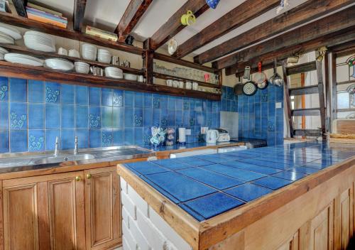 a kitchen with blue tiled walls and a counter top at Blochdy in Dwyran