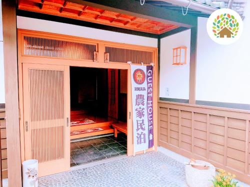 un bâtiment avec une porte ouverte et un panneau sur celui-ci dans l'établissement Farm stay inn Sanzaemon-tei 母屋GuestHouse Shiga-Takasima Traditional Japanese architecture house, à Takashima