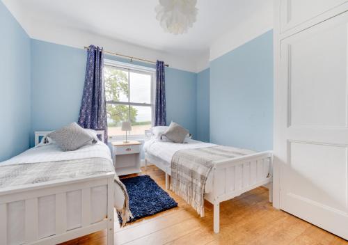 two beds in a room with blue walls and a window at Llwyncelyn in Llangadog