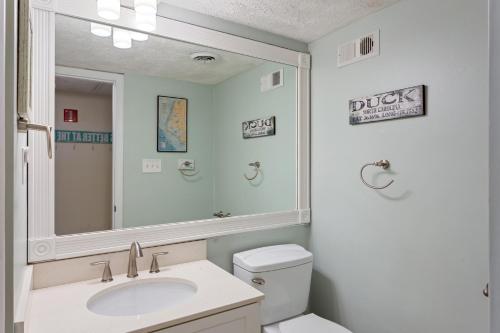 a bathroom with a sink and a mirror and a toilet at Oceanfront Shared Pool C102A Sea over the Dune in Duck