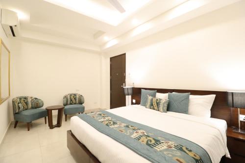 a bedroom with a large bed and two chairs at Ahuja Residency City Centre in Gurgaon