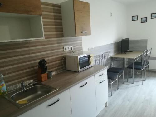 een keuken met een wastafel en een tafel met stoelen bij Kossuth téri Nopara STUDIO apartman in Tiszafüred