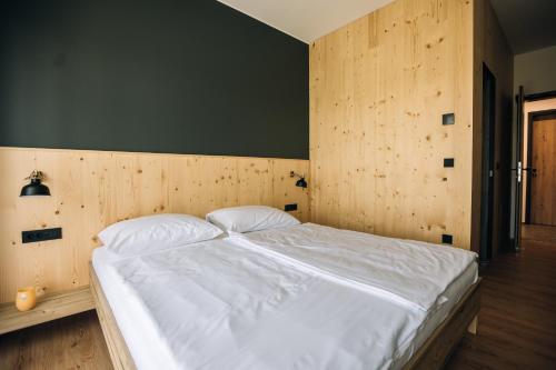 a bedroom with a white bed with a wooden wall at Postcard Country Apartments in Spodnji Duplek
