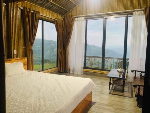 um quarto com uma cama e janelas grandes em Homstay Gốc Vải em Dan Mey