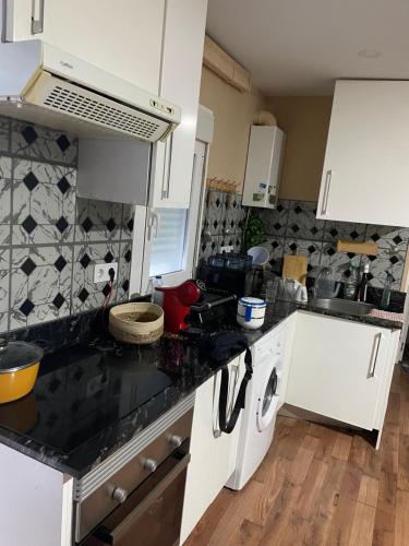 cocina con armarios blancos y encimera negra en keiny apartamento, en Getafe