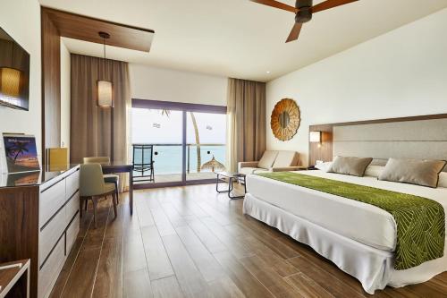 ダール環礁にあるRiu Palace Maldivas- All Inclusiveの大きなベッドとテーブルが備わるホテルルームです。