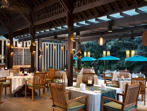 ein Restaurant mit weißen Tischen, Stühlen und blauen Sonnenschirmen in der Unterkunft The Samaya Ubud in Ubud