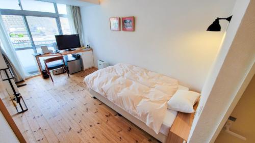 a bedroom with a bed and a desk with a television at Amakusa Santacoming Hotel in Amakusa
