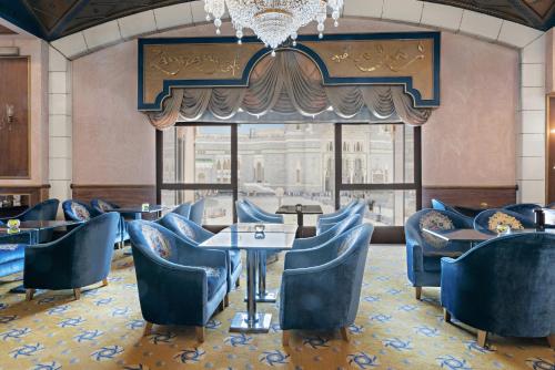 a restaurant with blue chairs and tables and a chandelier at InterContinental Dar Al Tawhid Makkah by IHG in Makkah