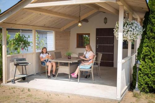 two women sitting at a table on a patio at Bungalow in Miedzyzdroje with a terrace in Międzyzdroje