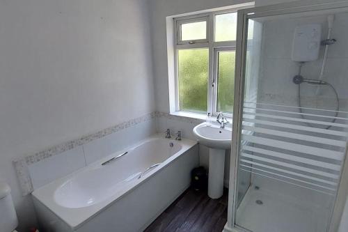ein weißes Badezimmer mit einer Badewanne und einem Waschbecken in der Unterkunft LoveLea Properties, House in Wolverhampton in Fallings Park