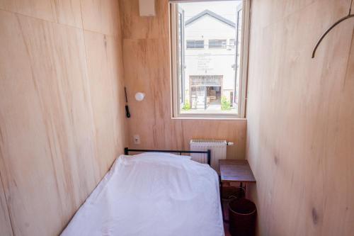 a small room with a bed and a window at BEACH AND FIELD INN in Sapporo