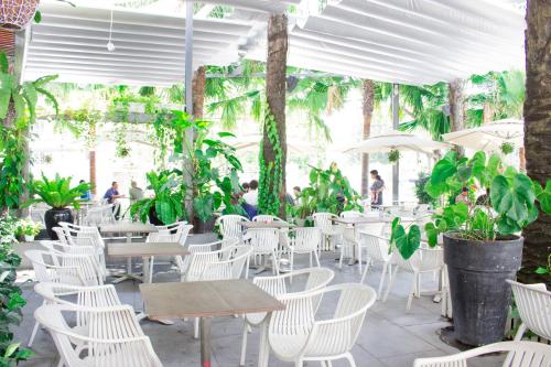 un restaurante con sillas blancas, mesas y plantas en International Hotel, en Can Tho