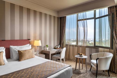 a hotel room with a bed and a desk and a window at Kaya Izmir Thermal & Convention in Izmir