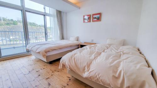a bedroom with two beds and a large window at Amakusa Santacoming Hotel in Amakusa