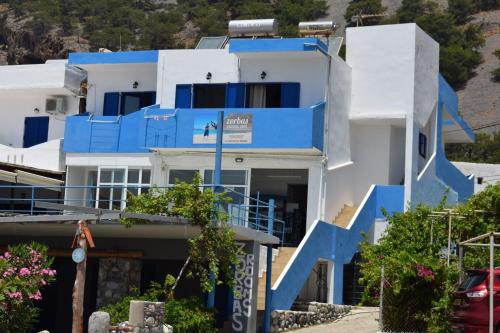 a blue and white house with blue stairs at Zorbas Studios in Agia Roumeli