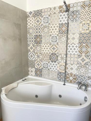 a white bath tub in a bathroom with a tile wall at A Casa dei Miei in Otranto