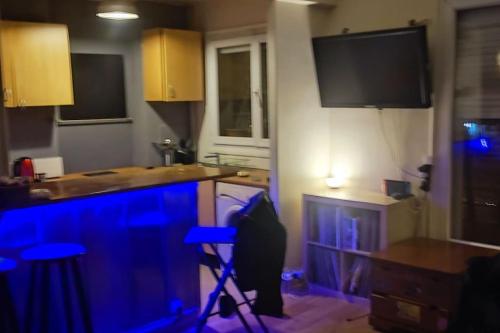 cocina con luces azules en la encimera y TV en studio idéal de voyage. en Gentilly