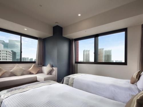 una camera con due letti, un divano e finestre di Hotel Villa Fontaine Grand Tokyo-Tamachi a Tokyo