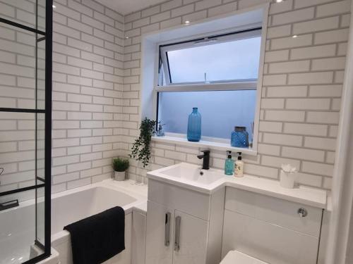 ein Bad mit einem Waschbecken, einer Badewanne und einem Fenster in der Unterkunft Home from home in Maryport in Maryport