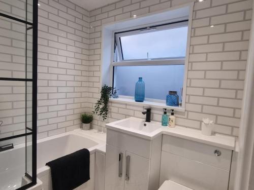 un bagno con lavandino, vasca e finestra di Home from home in Maryport a Maryport