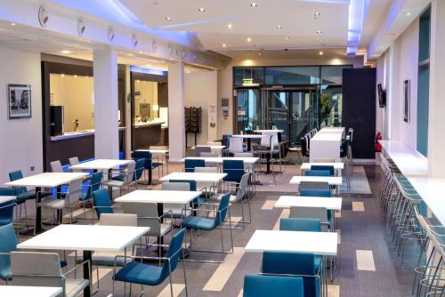 a dining room with tables and blue chairs at Holiday Inn Express Manchester City Centre Arena by IHG in Manchester