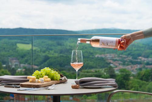 a person pouring a glass of wine on a table with grapes at Wine & SPA Hotel Chukara in Tryavna