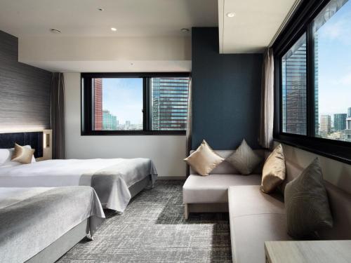 a hotel room with two beds and a couch at Villa Fontaine Grand Tokyo Tamachi in Tokyo