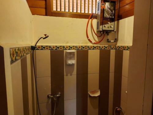 a bathroom with a shower with black and white tiles at Roemah Kayu Saragan Syariah Magelang Mitra RedDoorz in Banyurojo