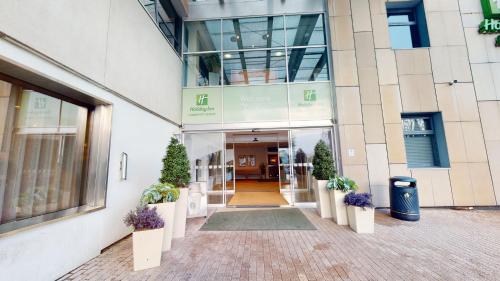 an entrance to a building with potted plants at Holiday Inn Cardiff City, an IHG Hotel in Cardiff