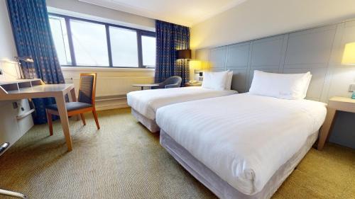 a hotel room with two beds and a desk at Holiday Inn Cardiff City Centre by IHG in Cardiff