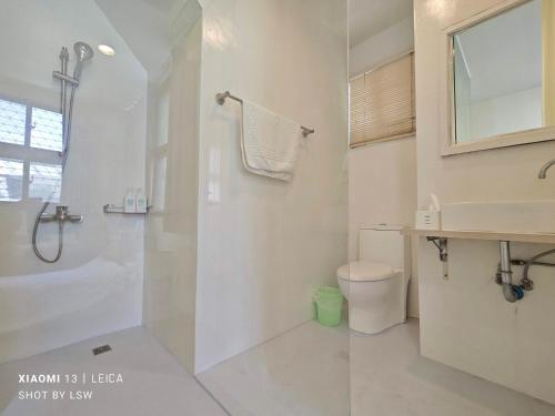 a white bathroom with a shower and a toilet at Honey House Tainan in Tainan