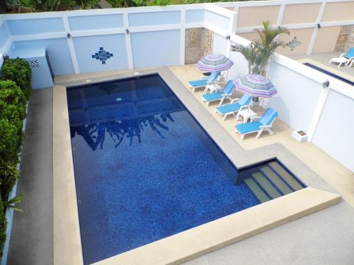 a swimming pool with chairs and umbrellas on a building at Majestic Villas Guesthouse Phuket. in Rawai Beach