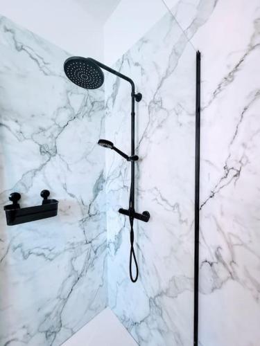 La salle de bains est pourvue d'une douche et d'un mur en marbre blanc. dans l'établissement Black&White Studio, à Mons