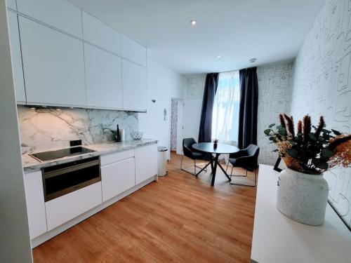 une cuisine avec des placards blancs et une table avec des chaises dans l'établissement Black&White Studio, à Mons