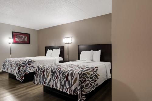 a hotel room with two beds with white sheets at Red Roof Inn Hartford- New Britain in New Britain