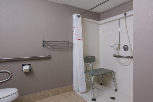 a bathroom with a shower and a chair in it at Red Roof Inn Hartford- New Britain in New Britain