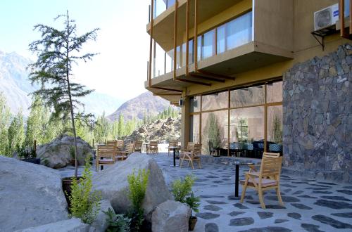 un edificio con sillas, mesas y montañas de fondo en Ambiance Resort Hunza, en Hunza