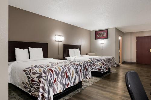 a hotel room with two beds and a chair at Red Roof Inn Hartford- New Britain in New Britain