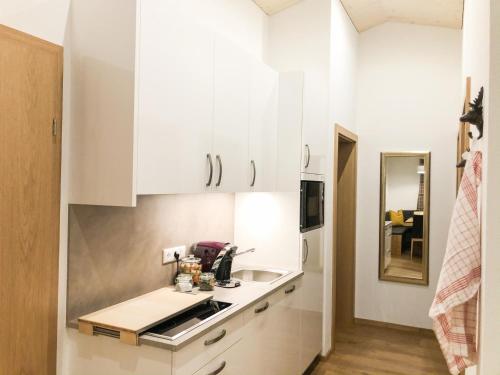 a kitchen with white cabinets and a sink at Woodpecker Chalets in Klösterle