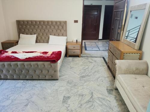 a bedroom with a bed and a couch and a mirror at Hotel Red Roof & Restaurant in Abbottābād