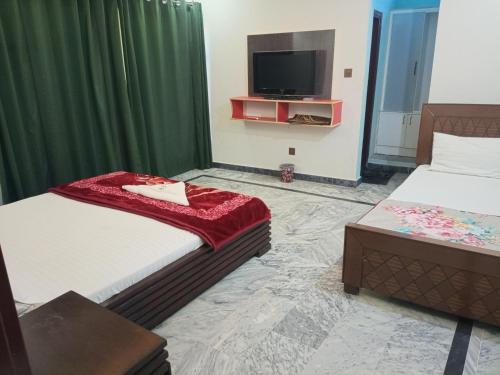 a bedroom with two beds and a flat screen tv at Hotel Red Roof & Restaurant in Abbottābād