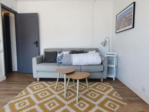 a living room with a couch and two tables at Studio, proche du Touquet, tout équipé à 100m de la plage in Stella-Plage