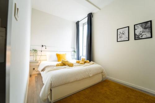 ein weißes Schlafzimmer mit einem großen Bett und gelben Kissen in der Unterkunft Yellow Two in Mons