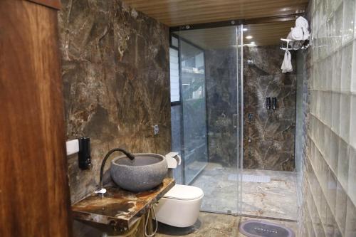 ein Bad mit einer Dusche, einem Waschbecken und einem WC in der Unterkunft Seaswan resort in Alibag