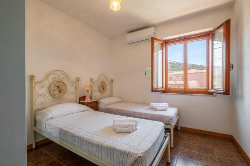 1 dormitorio con 2 camas y ventana en [5 Min Budoni]Terrazzo Vista Borgo & Self Check-In, en Tanaunella