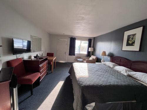 Habitación de hotel con cama, escritorio y TV. en BIGGS NU-VU MOTEL en Biggs Junction